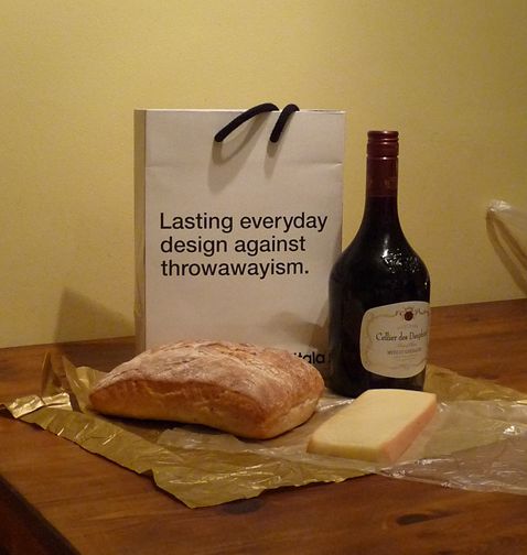 Wine, cheese and bread with a box saying "Lasting everyday design against throwawayism"